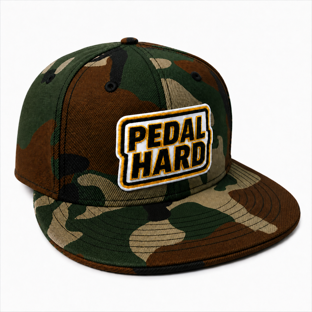 A flat-brim snapback cap in a green, brown, and beige camouflage pattern, featuring a prominent rectangular embroidered patch on the front that reads 'PEDAL HARD' in black letters with a gold outline.